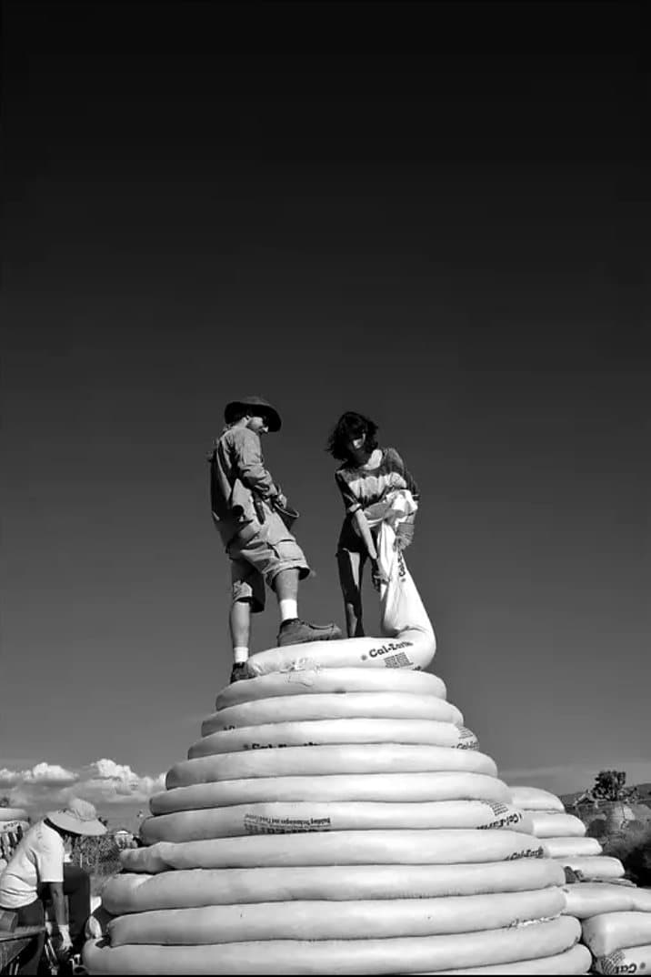 Samantha Jimenez and a volunteer stand on top of an earthbag dome under construction in California.