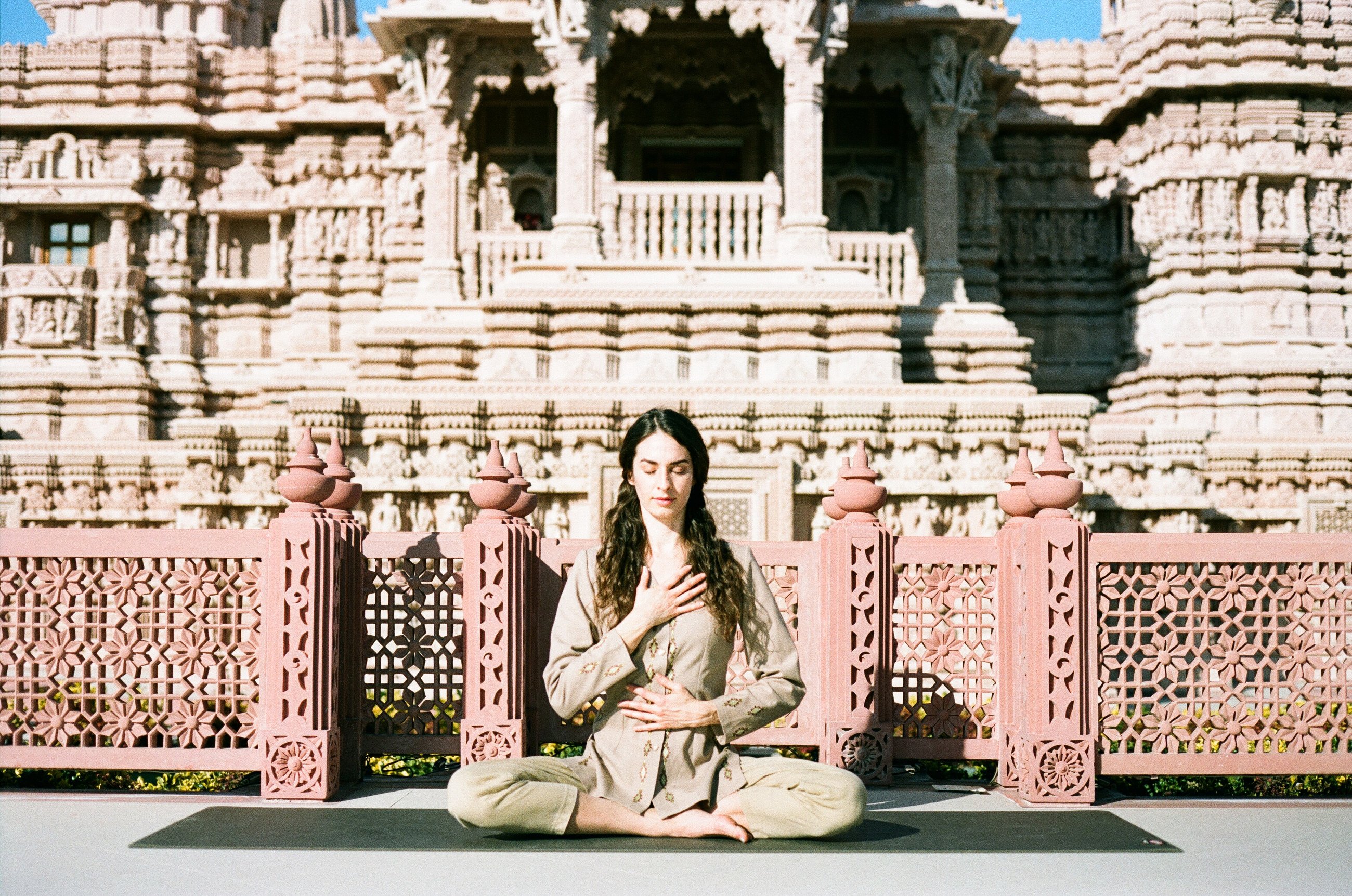 Samantha Jimenez, founder of Volna Global, meditates on a mat in front of a carved sandstone temple.